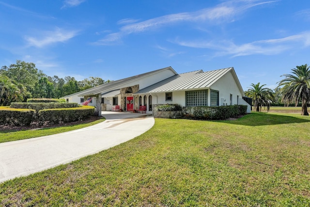 3120 SE Downwinds Rd, Jupiter, FL 33478 - single story home featuring a standing seam roof, a front yard, metal roof, driveway, and stucco siding
