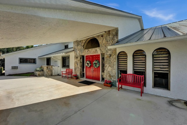 3120 SE Downwinds Rd, Jupiter, FL 33478 - doorway to property with metal roof, a standing seam roof, stone siding, and stucco siding