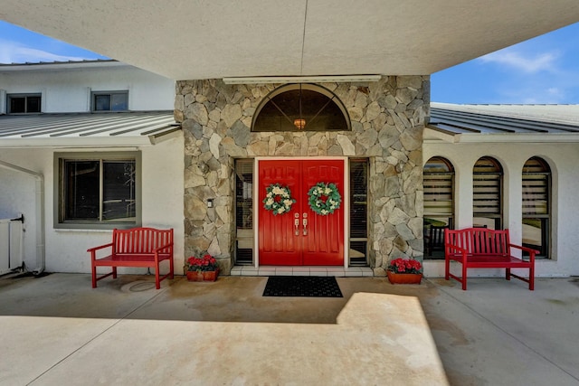3120 SE Downwinds Rd, Jupiter, FL 33478 - view of exterior entry with stucco siding, a standing seam roof, metal roof, and stone siding