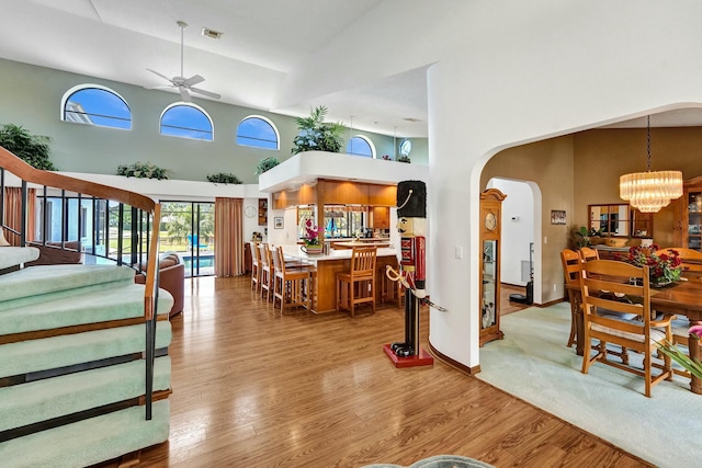 3120 SE Downwinds Rd, Jupiter, FL 33478 - living room featuring visible vents, a towering ceiling, arched walkways, wood finished floors, and ceiling fan with notable chandelier