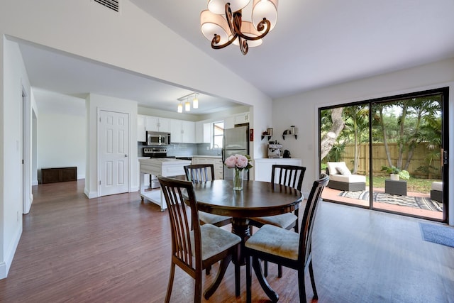 dining space with a chandelier, dark wood-style floors, vaulted ceiling, and plenty of natural light