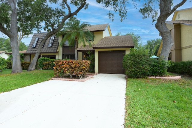 view of front of property featuring driveway, stucco siding, an attached garage, and a front lawn