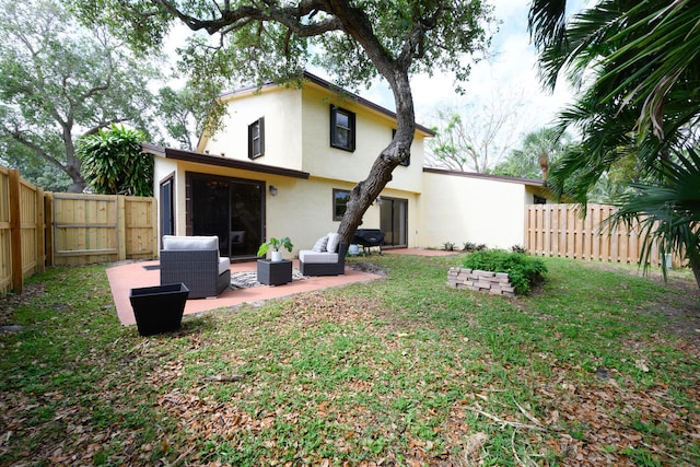 back of house featuring stucco siding, outdoor lounge area, a patio area, a fenced backyard, and a lawn