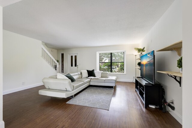 living area with baseboards, wood finished floors, and stairs