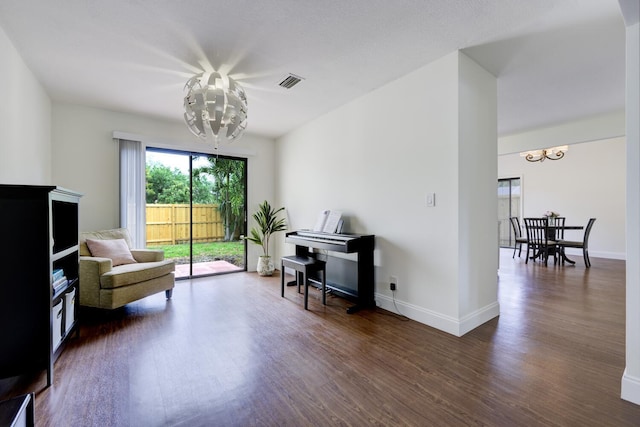 living area with a notable chandelier, baseboards, visible vents, and wood finished floors