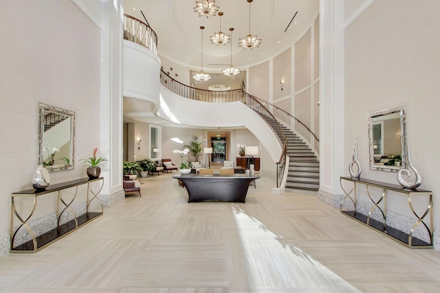 foyer featuring baseboards, stairs, an inviting chandelier, and a high ceiling