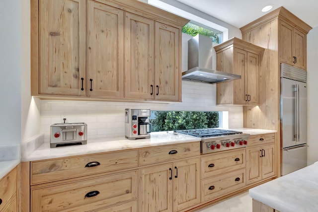 kitchen featuring appliances with stainless steel finishes, light brown cabinets, wall chimney range hood, and decorative backsplash