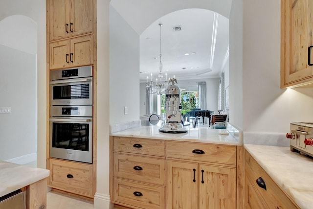kitchen with light brown cabinetry, visible vents, arched walkways, and stainless steel double oven