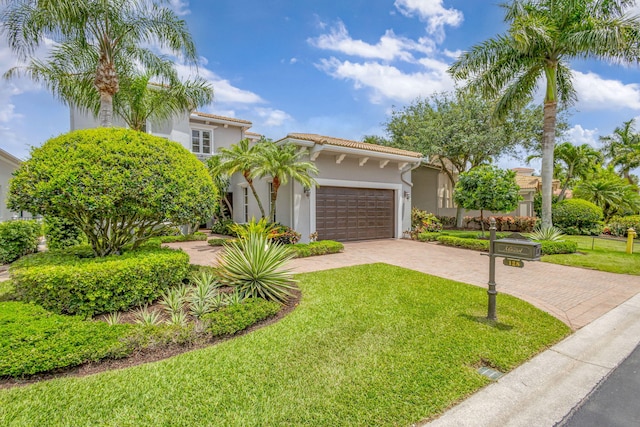 mediterranean / spanish-style house with a front lawn, stucco siding, decorative driveway, a tiled roof, and an attached garage