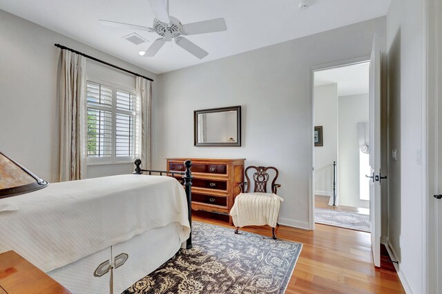bedroom with ceiling fan, wood finished floors, and baseboards