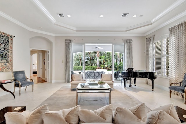 living room featuring light tile patterned floors, a raised ceiling, visible vents, and arched walkways