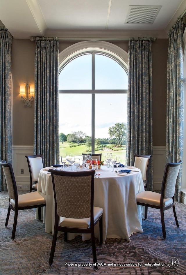 dining space featuring a healthy amount of sunlight, visible vents, a wainscoted wall, and a decorative wall