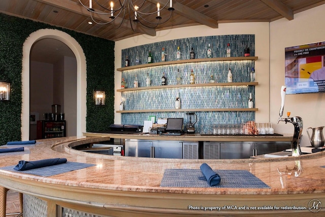 bar featuring a chandelier, arched walkways, beam ceiling, wooden ceiling, and indoor wet bar