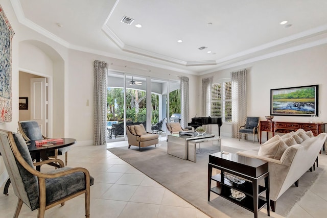 living area featuring light tile patterned floors, visible vents, a tray ceiling, arched walkways, and ornamental molding