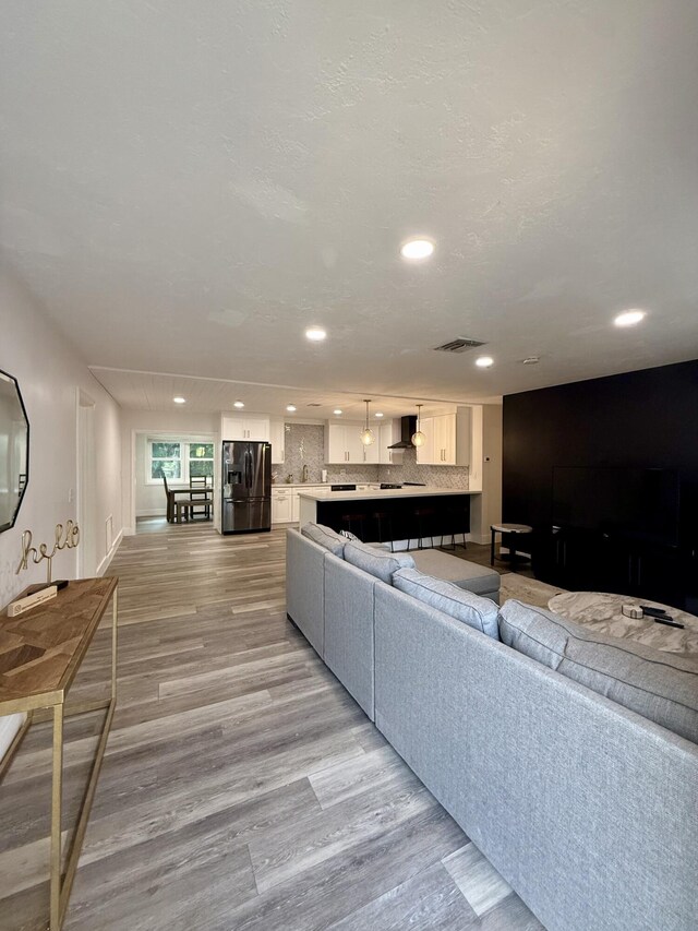 living area featuring recessed lighting, light wood finished floors, and visible vents