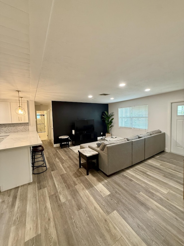 living area featuring recessed lighting, visible vents, light wood-type flooring, and baseboards