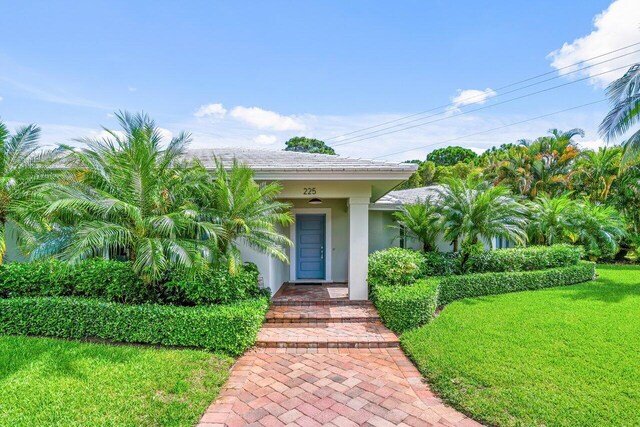 225 NW 11th St, Delray Beach, FL 33444 - doorway to property with stucco siding and a yard