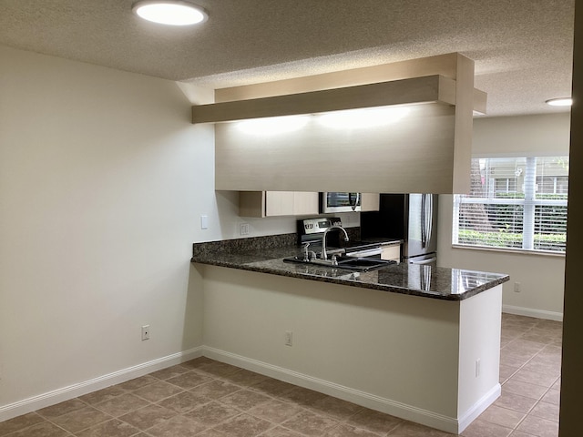 2415 SW Danbury Ln, Palm City, FL 34990 - kitchen with a peninsula, a textured ceiling, a sink, appliances with stainless steel finishes, and light tile patterned floors