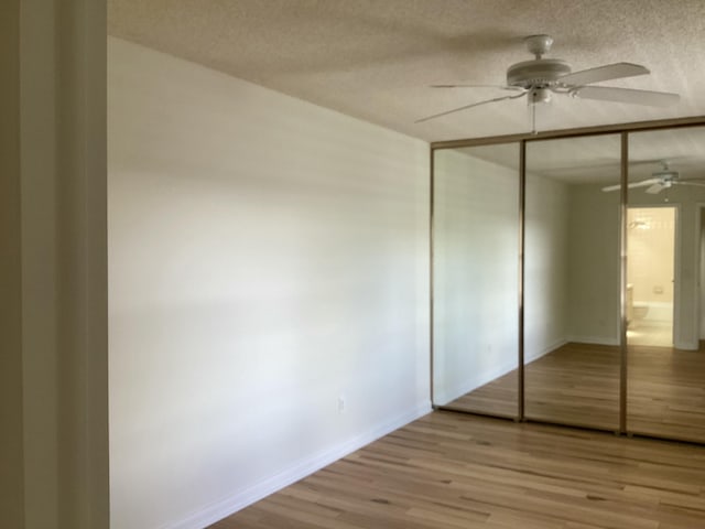 2415 SW Danbury Ln, Palm City, FL 34990 - unfurnished bedroom featuring a textured ceiling, a ceiling fan, baseboards, wood finished floors, and a closet