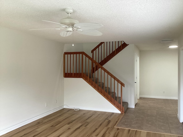 2415 SW Danbury Ln, Palm City, FL 34990 - staircase with a ceiling fan, a textured ceiling, visible vents, wood finished floors, and baseboards