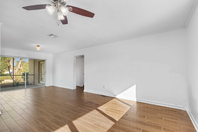 spare room with wood finished floors, ceiling fan, baseboards, visible vents, and crown molding