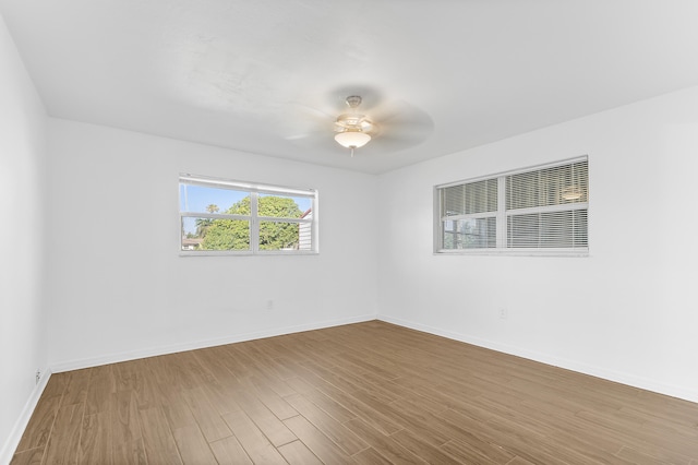 spare room featuring wood finished floors, ceiling fan, and baseboards