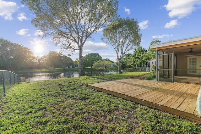 view of yard featuring a deck with water view, a fenced backyard, ceiling fan, and a sunroom