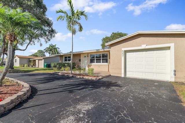 ranch-style home with driveway, a garage, and stucco siding