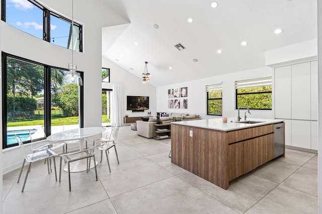 kitchen with a large island with sink, visible vents, a sink, modern cabinets, and high vaulted ceiling