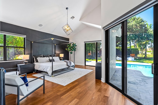 bedroom with multiple windows, wood finished floors, visible vents, and access to outside