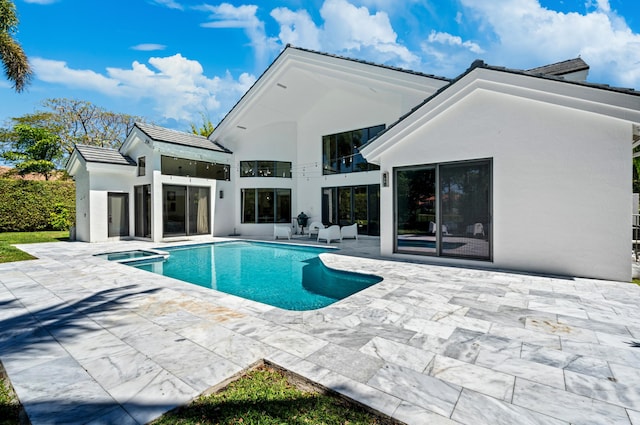 back of house featuring a fenced in pool, a tiled roof, a balcony, stucco siding, and a patio