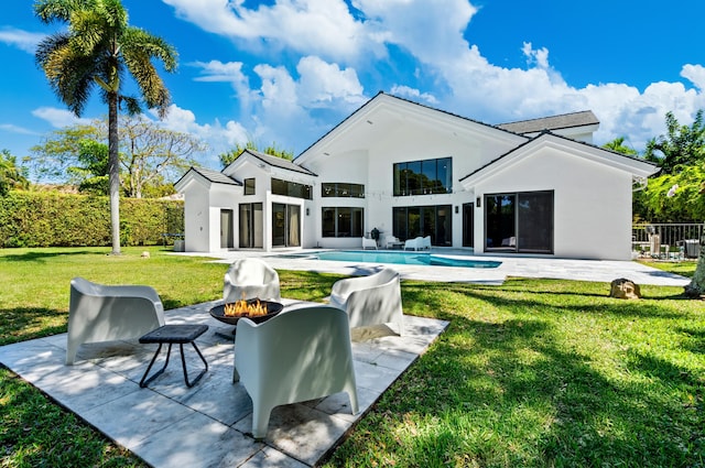 rear view of house with a patio area, a lawn, an outdoor fire pit, a fenced in pool, and stucco siding