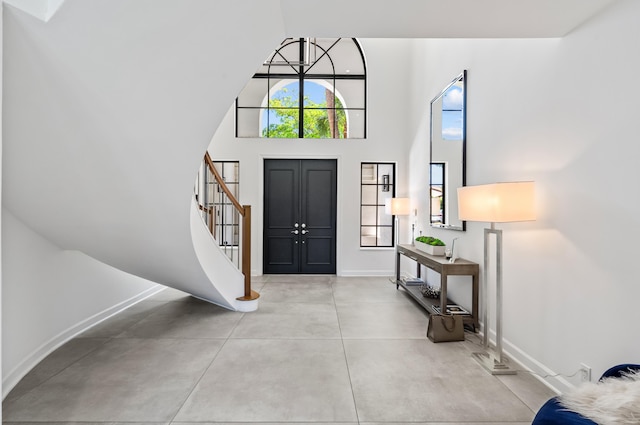 foyer entrance with baseboards, stairs, finished concrete flooring, and high vaulted ceiling