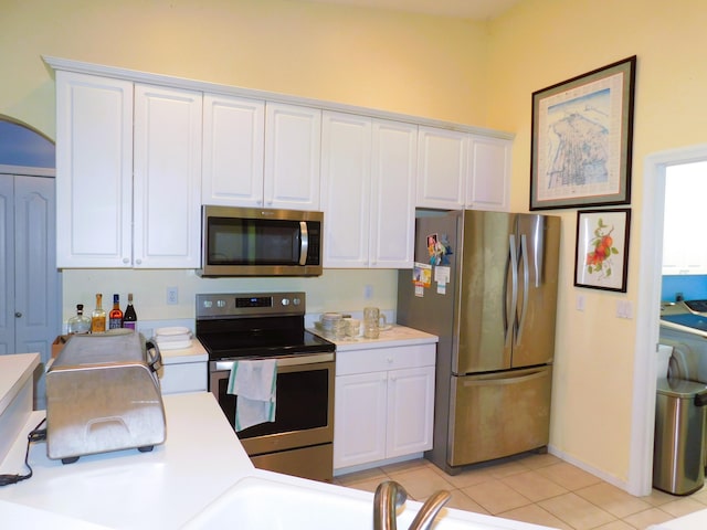 17609 72nd Rd N, The Acreage, FL 33470 - kitchen with light tile patterned floors, arched walkways, white cabinetry, appliances with stainless steel finishes, and light countertops
