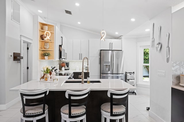 kitchen featuring baseboards, modern cabinets, a sink, appliances with stainless steel finishes, and a kitchen breakfast bar