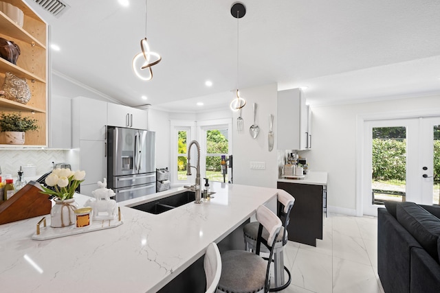 kitchen featuring visible vents, stainless steel refrigerator with ice dispenser, a sink, vaulted ceiling, and light stone countertops