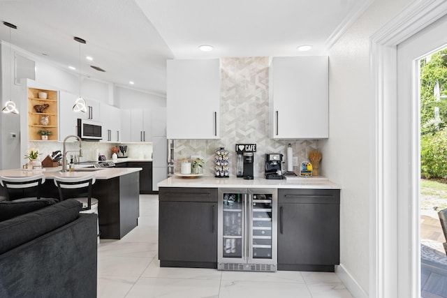 bar featuring white microwave, tasteful backsplash, a sink, beverage cooler, and decorative light fixtures