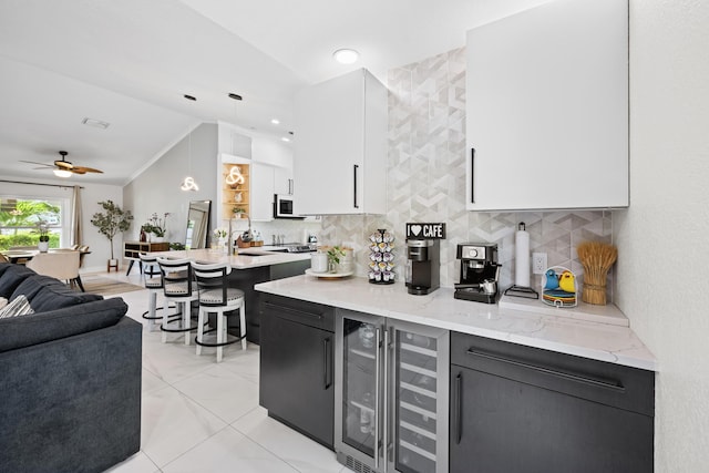 kitchen with light stone counters, open floor plan, white cabinetry, backsplash, and lofted ceiling