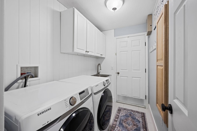 laundry room with cabinet space, washing machine and dryer, light tile patterned flooring, and a sink