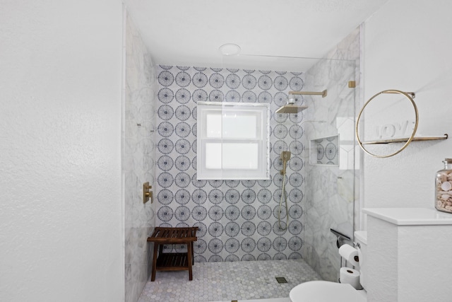full bathroom featuring a tile shower and toilet