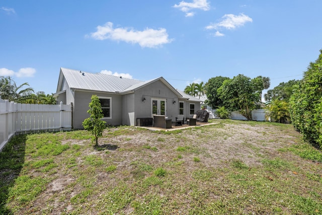 rear view of property featuring a patio, a fenced backyard, french doors, and stucco siding