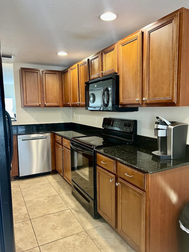 4220 Gator Trace Ave Unit 5E, Fort Pierce, FL 34982 - kitchen featuring dark stone counters, brown cabinetry, black appliances, light tile patterned floors, and recessed lighting
