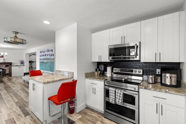 944 Hansen St, West Palm Beach, FL 33405 - kitchen featuring appliances with stainless steel finishes, light wood-style flooring, backsplash, white cabinets, and recessed lighting