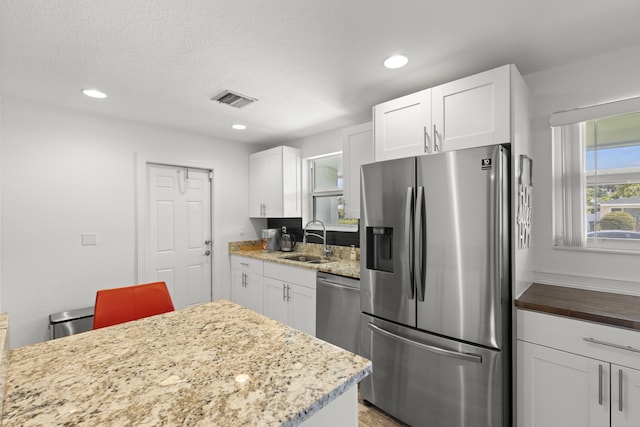 944 Hansen St, West Palm Beach, FL 33405 - kitchen featuring stainless steel appliances, a sink, white cabinetry, recessed lighting, and light stone counters