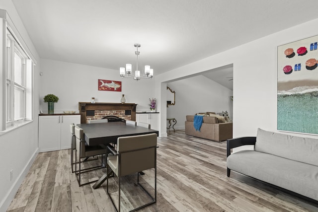 944 Hansen St, West Palm Beach, FL 33405 - dining space with light wood-style flooring, a chandelier, baseboards, and a fireplace