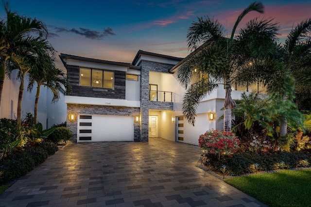 17045 Five Waters Ave, Boca Raton, FL 33496 - view of front of home featuring a balcony, stucco siding, stone siding, decorative driveway, and a garage
