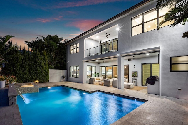 17045 Five Waters Ave, Boca Raton, FL 33496 - back of property at dusk with an outdoor hangout area, stucco siding, a ceiling fan, and a balcony
