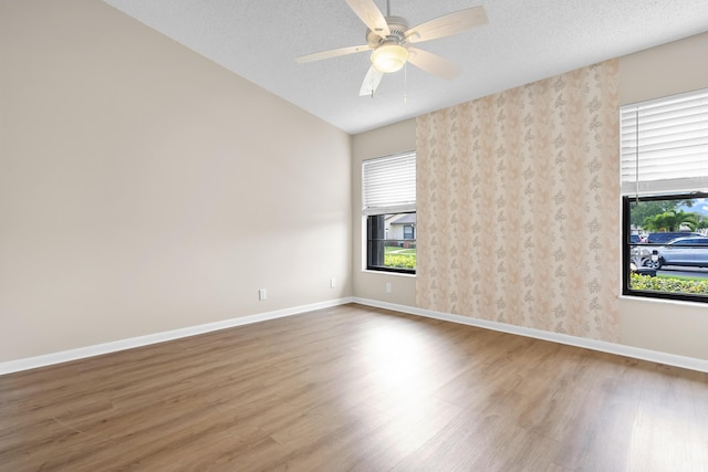 unfurnished room with ceiling fan, a textured ceiling, wood finished floors, and baseboards