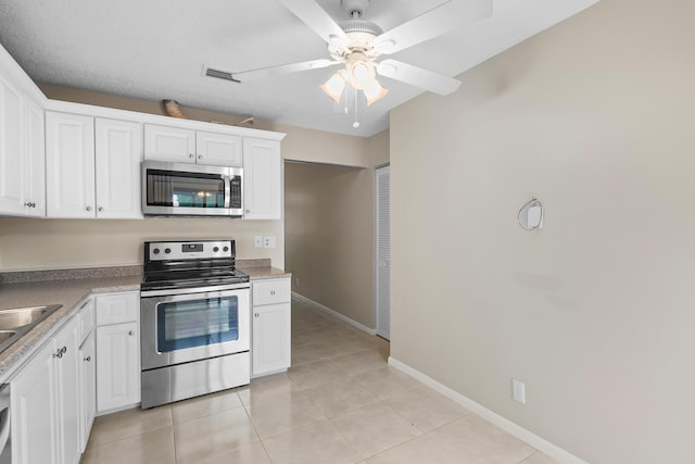 kitchen featuring light tile patterned floors, white cabinetry, baseboards, and appliances with stainless steel finishes