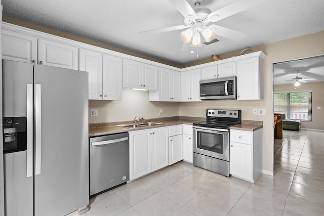 kitchen with light tile patterned floors, a ceiling fan, white cabinets, stainless steel appliances, and a sink
